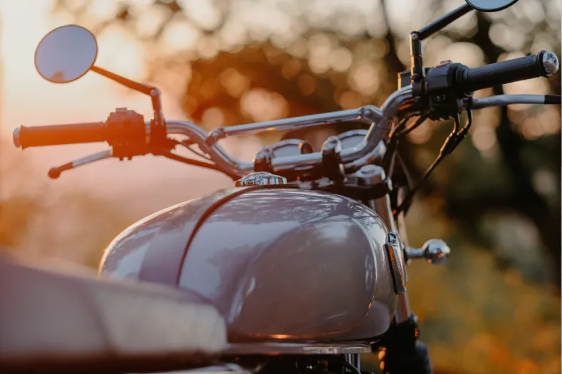Tanque e guidão de motocicleta fotografados ao entardecer